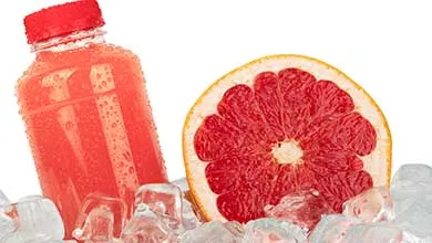 Juice bottle and grapefruit next to it in ice