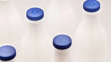 Close-up of several white plastic bottles with blue caps, viewed from above.
