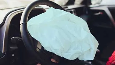 Close-up of a white airbag fully inflated in a car’s steering wheel.