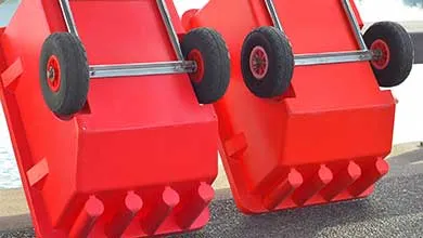 Two large red plastic bins are upside down, revealing their black wheels on metal axles.